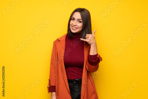 Young woman with coat making phone gesture. Call me back sign