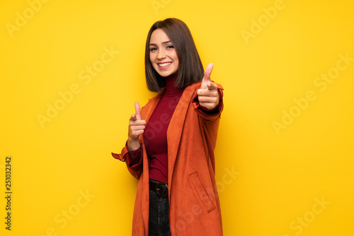 Young woman with coat points finger at you while smiling © luismolinero