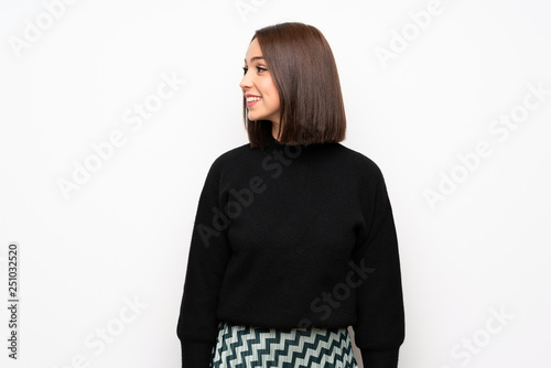 Young woman over white wall looking to the side