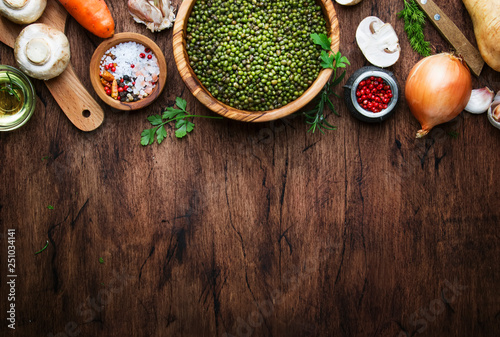 Ingredients for cooking green lentils with mushrooms and vegetables, spices and herbs, vintage wooden kitchen table, food cooking background, place for text. Vegan or vegetarian food