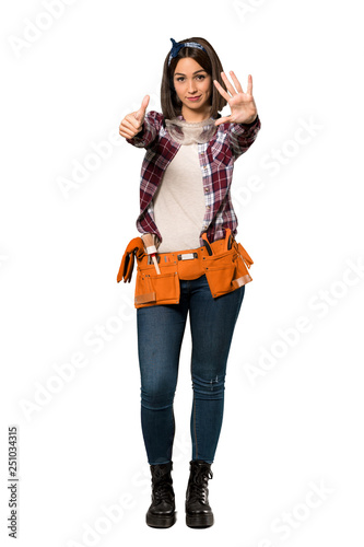 A full-length shot of a Young worker woman counting six with fingers over isolated white background