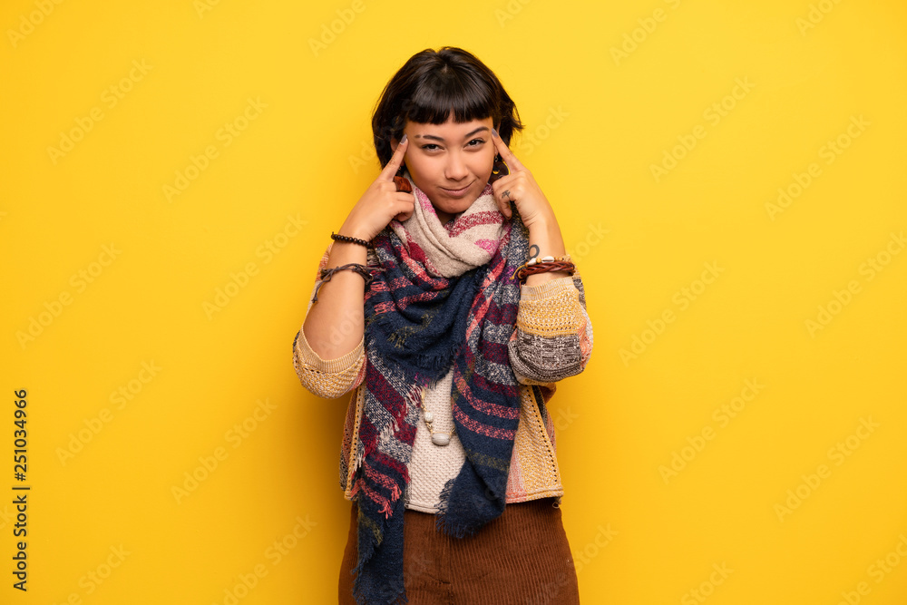 Young hippie woman over yellow wall having doubts and thinking Young hippie woman over yellow wall having doubts and thinking