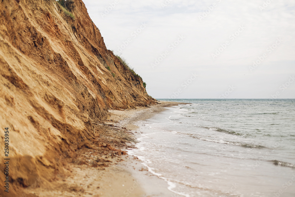 Beautiful view of sandy cliff near sea beach. Landscape of beach cliff and waves. Summer vacation concept. Exploring interesting places