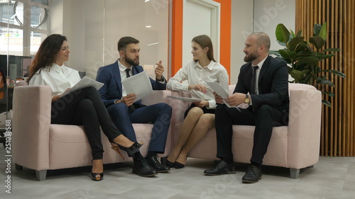 Two women and two men sit on the couch in their break and talk, office workers, a metropolis, offices, office workers. Bussines meeting discuss 