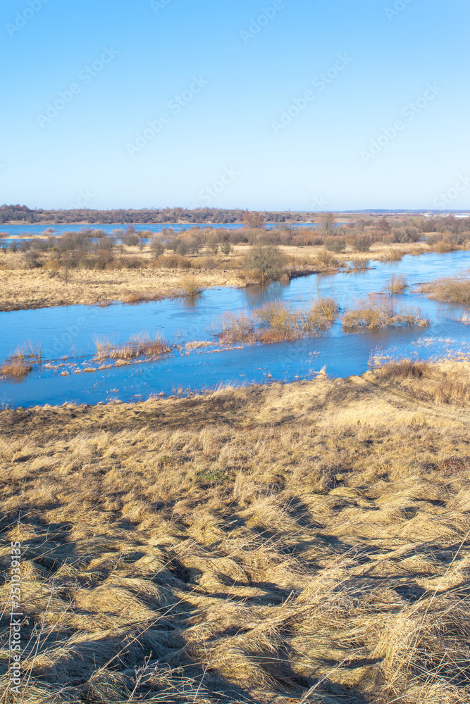 scenic landscape with hills covered with yellow grass and blue river under a clear sunny sky