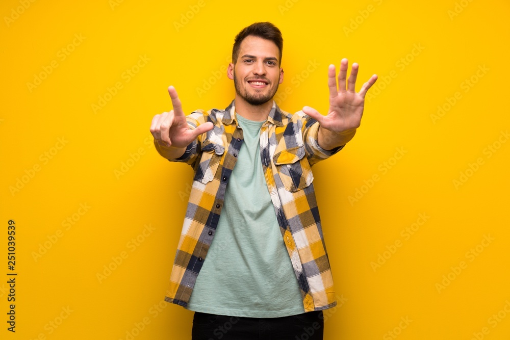 Handsome man over yellow wall counting seven with fingers Handsome man over yellow wall counting seven with fingers