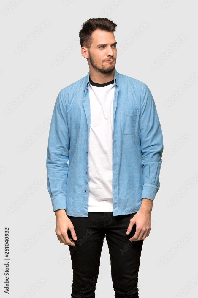 Handsome man with confuse face expression while bites lip over grey background Handsome man with confuse face expression while bites lip over grey background