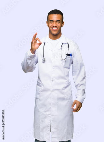 Young afro american man doctor showing an ok sign with fingers on isolated background