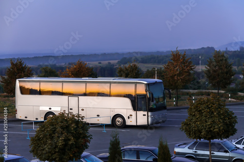 White tourist bus on parking place rural area warm summer sunset day on blue sky background copy space