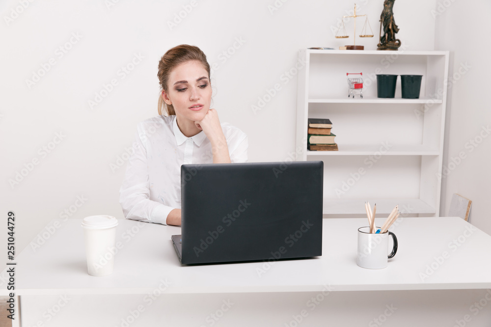 Young businesswoman in a white blouse sitting in an office. Office worker sitting infront of black computer. Coffee in office. Young businesswoman in a white blouse sitting in an office. Office worker sitting infront of black computer. Coffee in office.