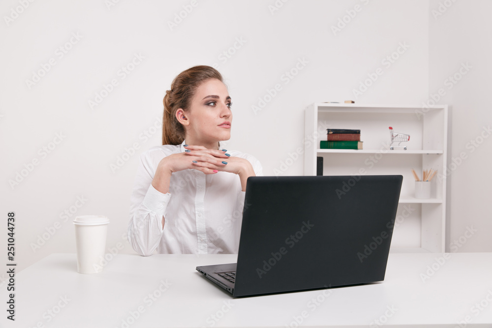 Young businesswoman in a white blouse sitting in an office. Office worker sitting infront of black computer. Coffee in office. Young businesswoman in a white blouse sitting in an office. Office worker sitting infront of black computer. Coffee in office.