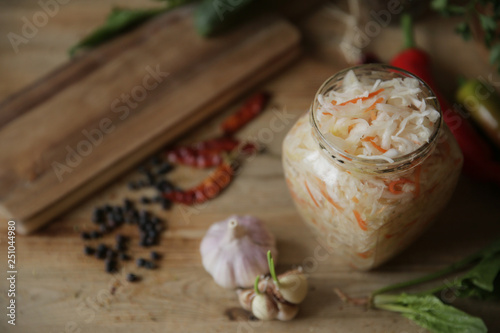 sauerkraut in a glass jar on a wooden table with spices and herbs with copy space for text. Top view.