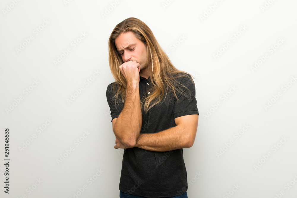 Blond man with long hair over white wall having doubts Blond man with long hair over white wall having doubts