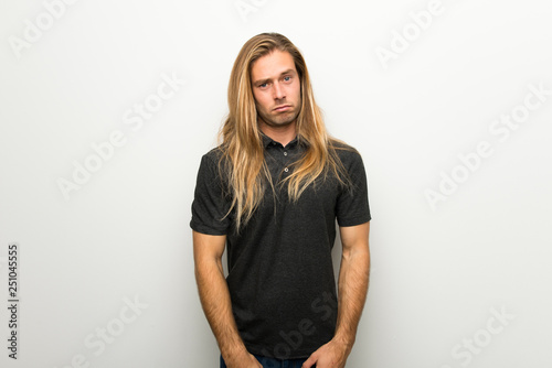 Bild auf Leinwand Blond man with long hair over white wall with sad and depressed expression