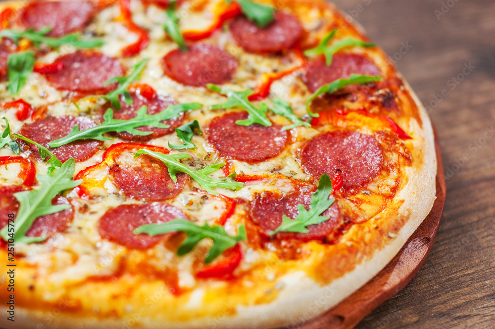 Pepperoni Pizza with Mozzarella cheese, salami, Tomatoes, pepper, Spices and Fresh arugula. Italian pizza on wooden table background Pepperoni Pizza with Mozzarella cheese, salami, Tomatoes, pepper, Spices and Fresh arugula. Italian pizza on wooden table background