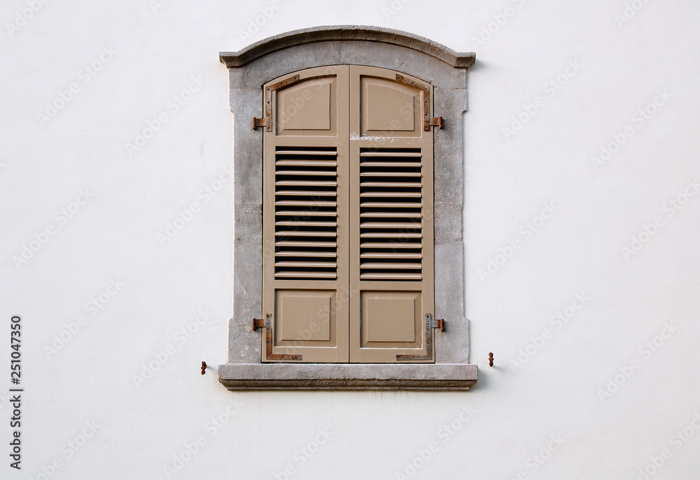 arched window with wooden shutters on a white wall