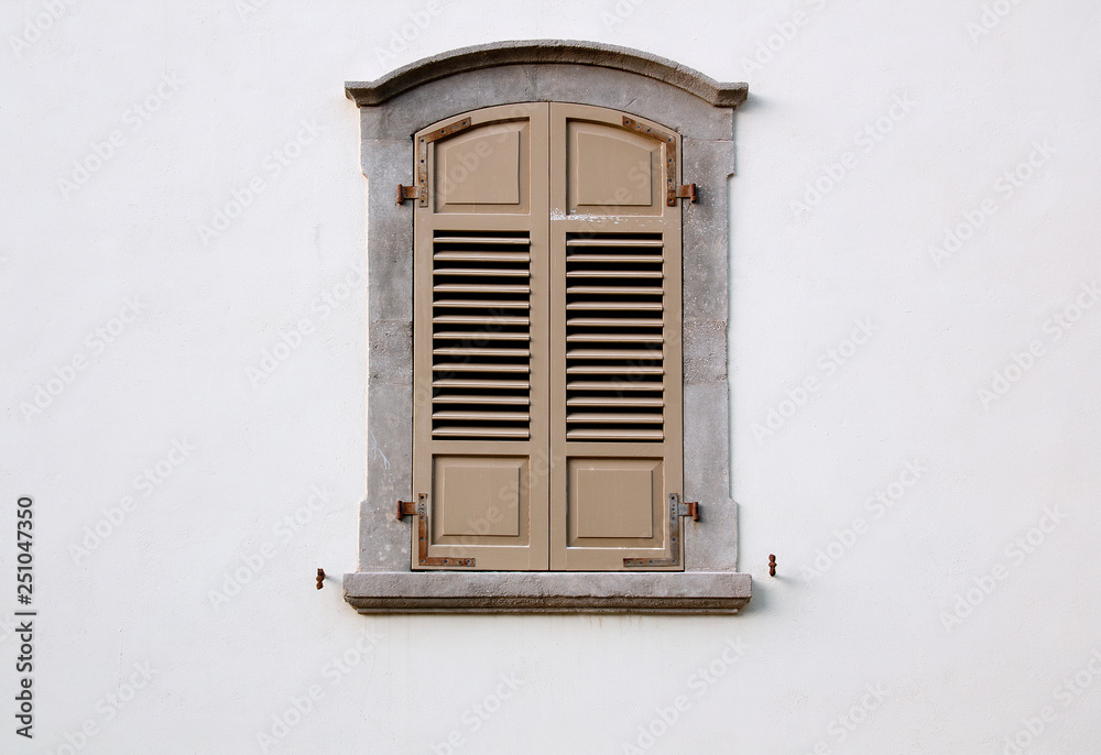 Fototapeta premium arched window with wooden shutters on a white wall