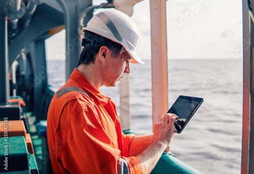 Marine chief officer or captain on deck of vessel or ship watching digital tablet. Internet and home connection at sea. photo