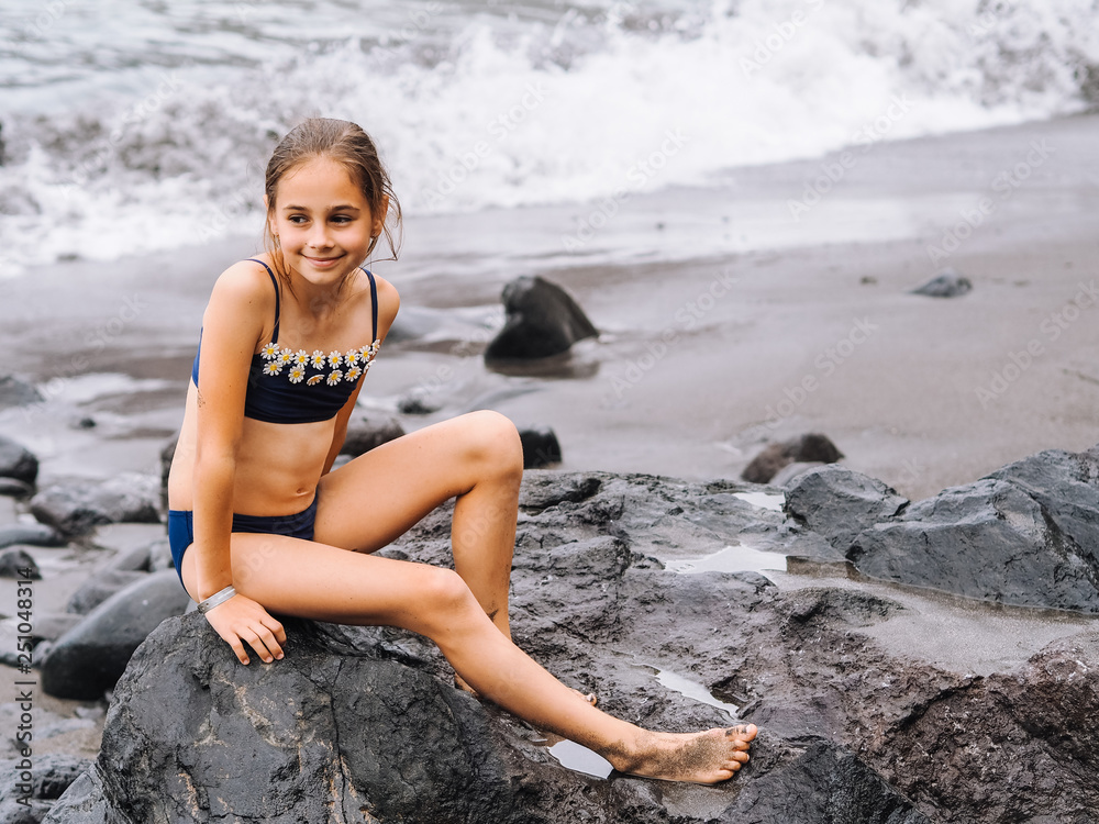 Girl play on a beach in the sea waves and playing on the volcanic sand beach Girl play on a beach in the sea waves and playing on the volcanic sand beach