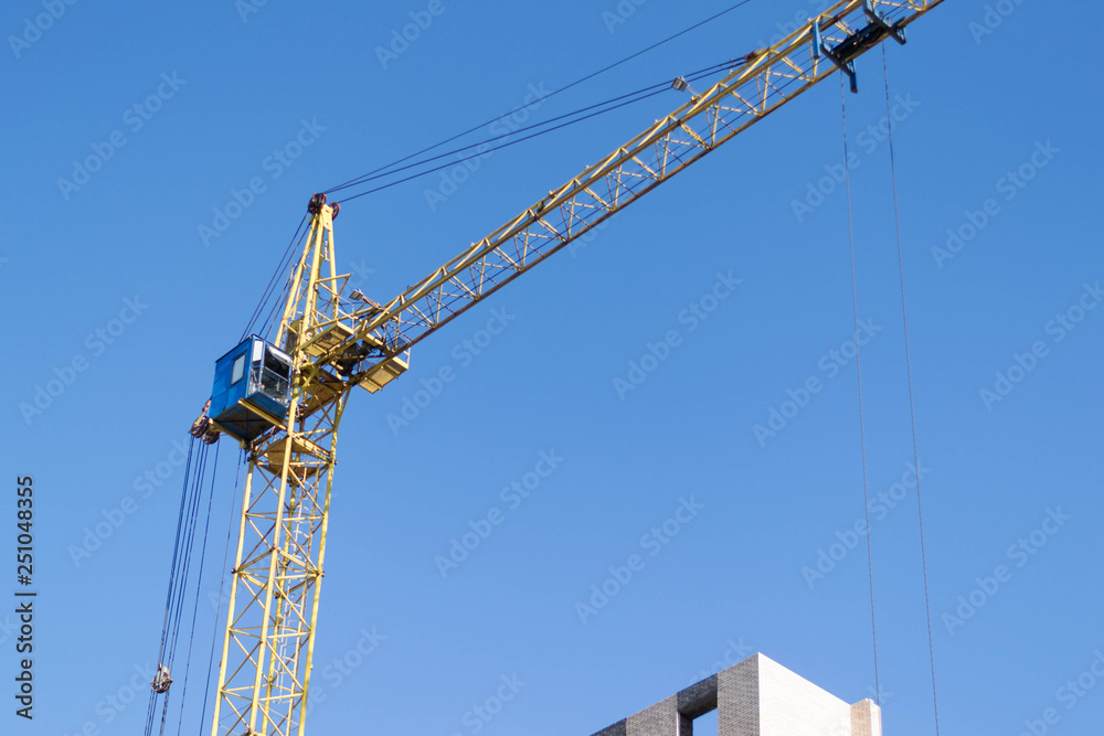 Crane and building under construction against blue sky