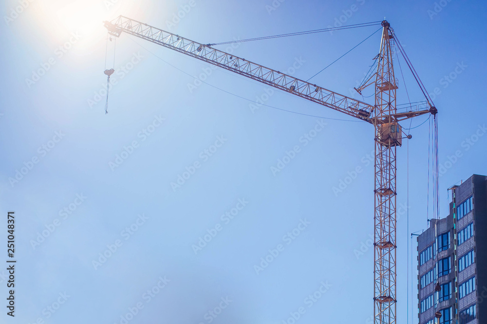 Crane and building under construction against blue sky Crane and building under construction against blue sky
