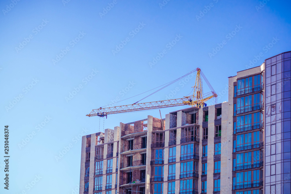Crane and building under construction against blue sky Crane and building under construction against blue sky