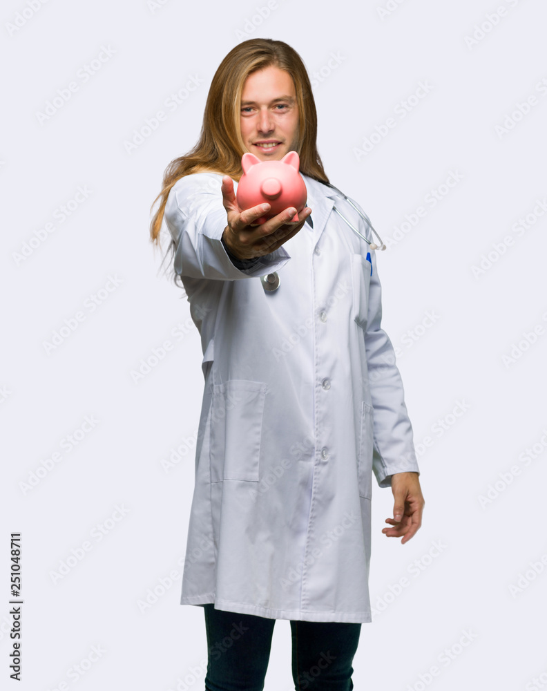 Doctor man holding a piggybank on isolated background Doctor man holding a piggybank on isolated background