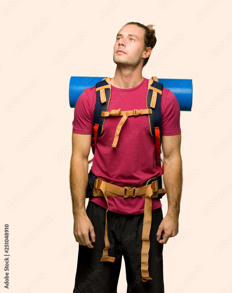 Hiker man with mountain backpacker looking up with serious face on isolated background Hiker man with mountain backpacker looking up with serious face on isolated background