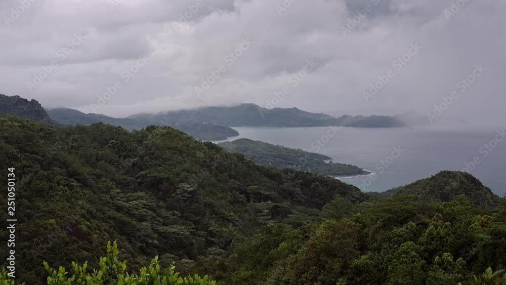 Green mountain on the island in cloudy rainy weather, the top of the mountain is hidden under white clouds, the view is at the top of the mountain. Green mountain on the island in cloudy rainy weather, the top of the mountain is hidden under white clouds, the view is at the top of the mountain.