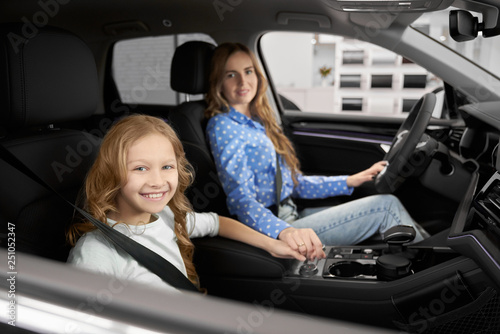 Mother and daughter sitting in front seats of new auto.
