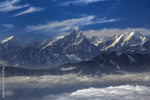 Edge of the Himalayas - view from Niubeishan Cattle Back Mountain in Sichuan Province, China. View on Clear day above the sea of clouds, blue sky. Himalayan snow capped high altitude mountains