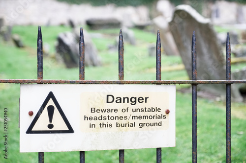 Vászonkép Unstable headstones memorials at burial ground gravestones danger sign