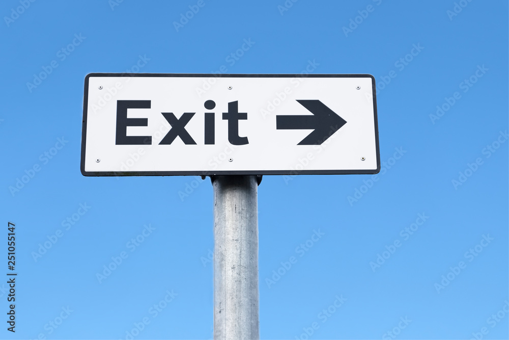 Exit arrow direction sign against blue sky Exit arrow direction sign against blue sky