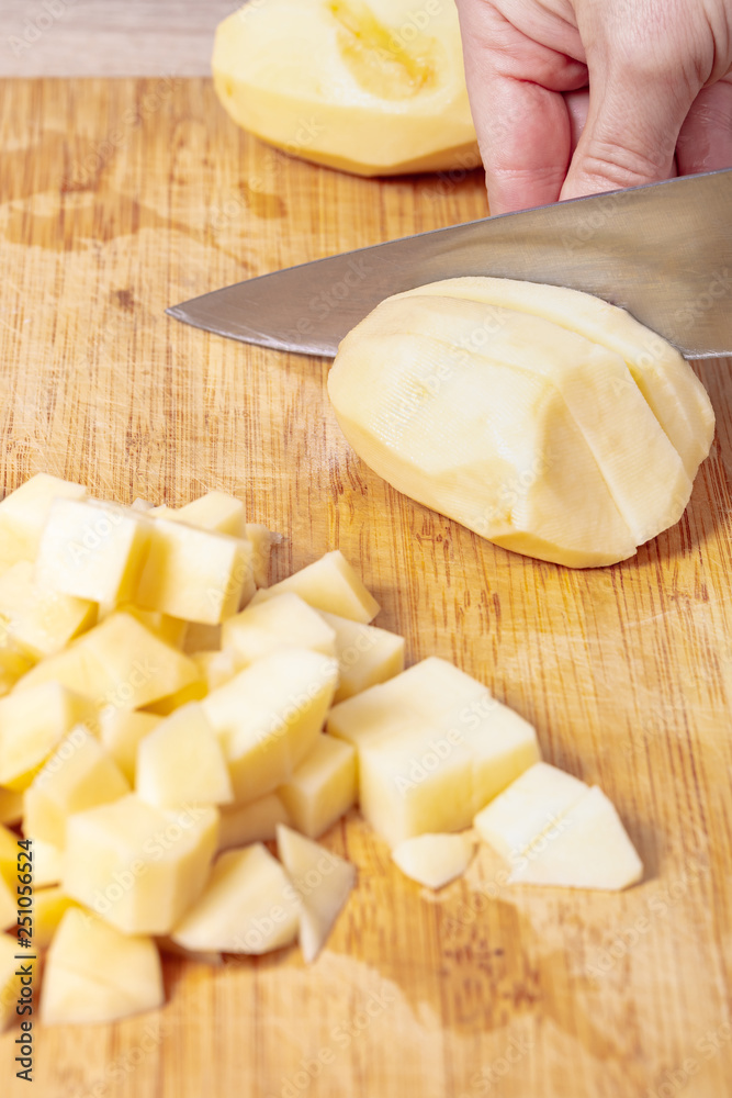 cook cuts potatoes on a wooden board cook cuts potatoes on a wooden board