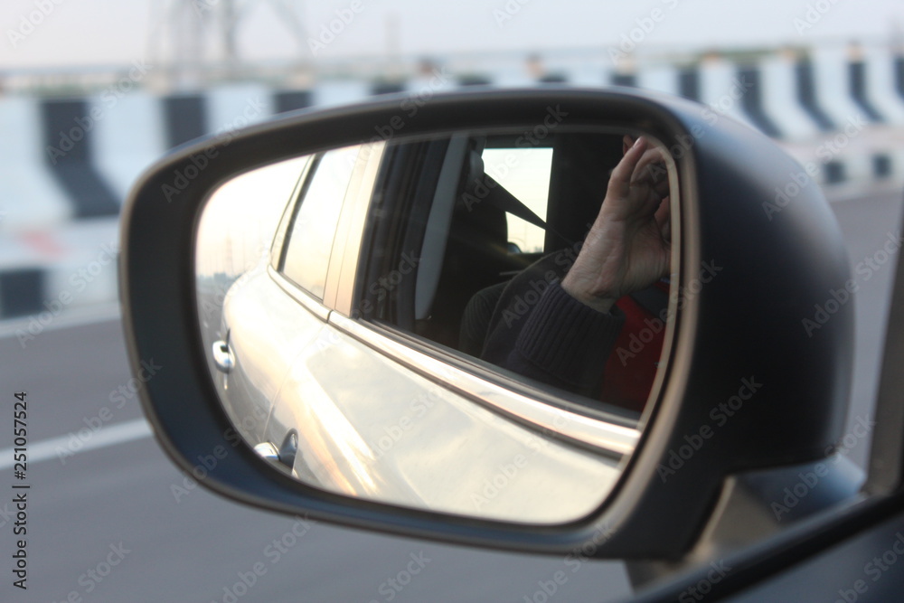A view of side view mirror of car on a highway.