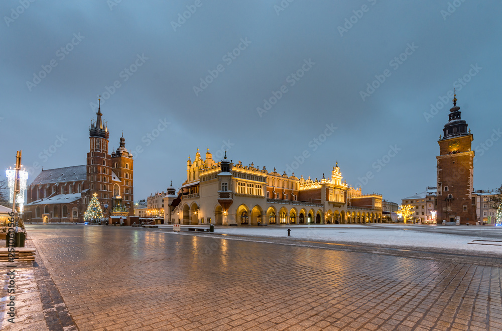 Naklejka premium Krakow, Poland, main market square, winter night, St Mary's church and Cloth Hall illuminated
