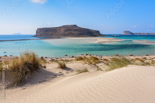 The white sand beside the sea, where the bottom can be seen, the beach with people. Beautiful mountains on a blue horizon. Incredible Balos. A landscape on a summer sunny day. Crete Island, Greece. photo