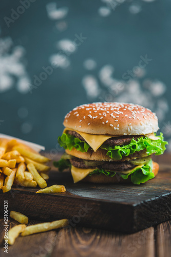 Burger with potatoes and dark beer on a wooden Board on a blue-gray background