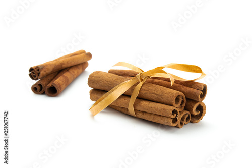 Cinnamon sticks wrapped with golden tape isolated on white background.