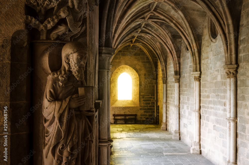 Detail of the medieval gothic cloisters of the cathedral of Evora, main city of the Alentejo region (Portugal) with an evangelist statue holding the bible