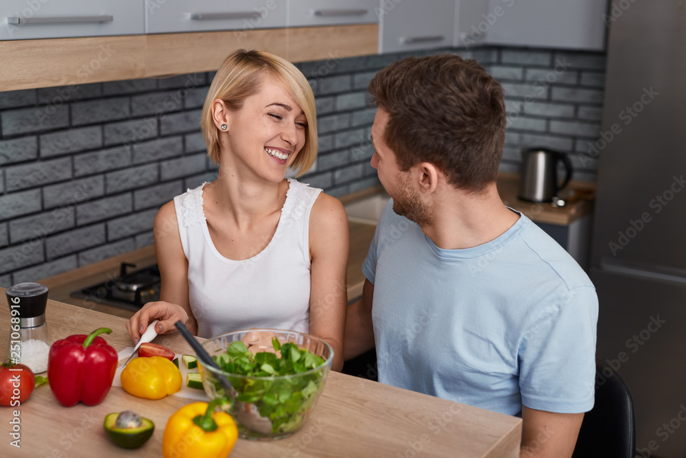 Content couple preparing vegetable salad together Content couple preparing vegetable salad together