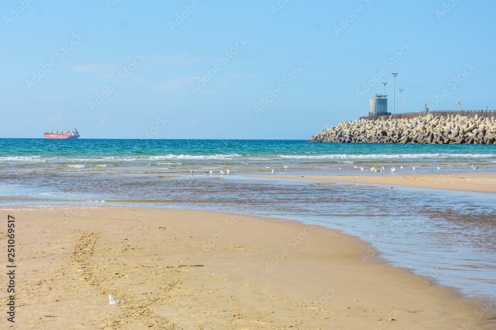 Stone breakwater, sandy beach, blue sea. Ashdod, Israel