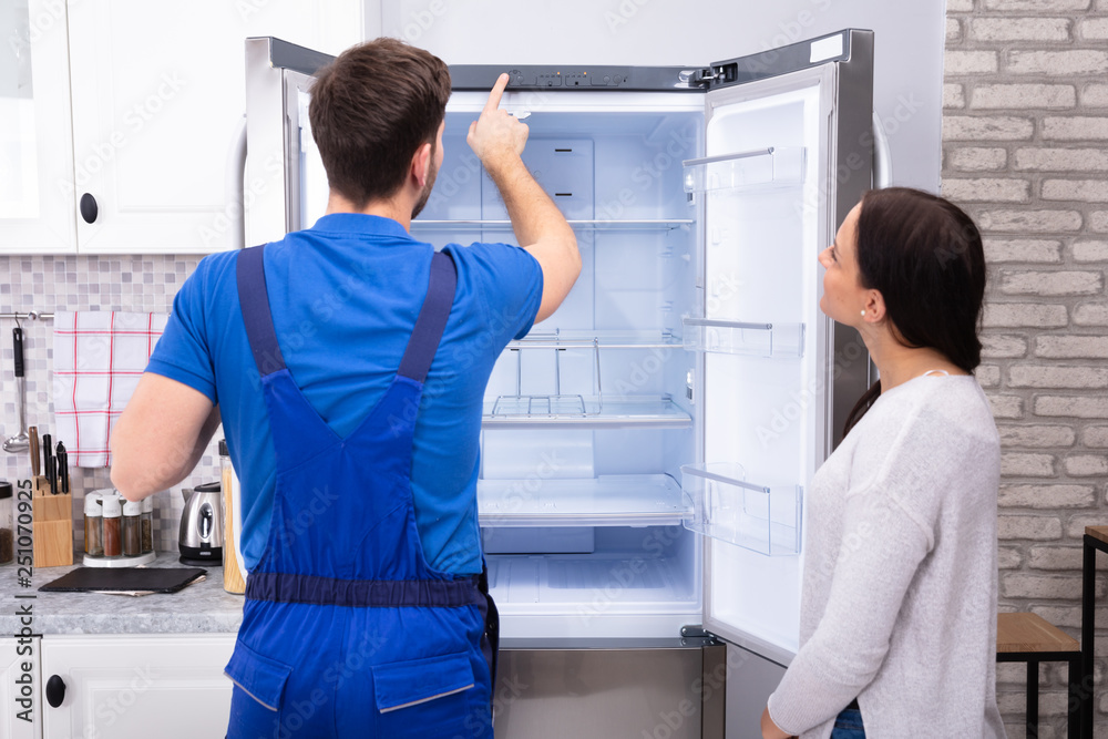 Serviceman Checking Temperature Of Refrigerator Serviceman Checking Temperature Of Refrigerator