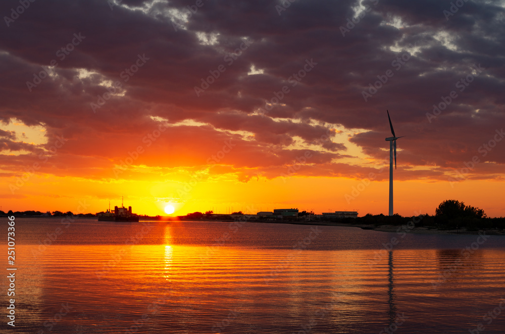 Renewable energy with wind turbines at the sea in sunset