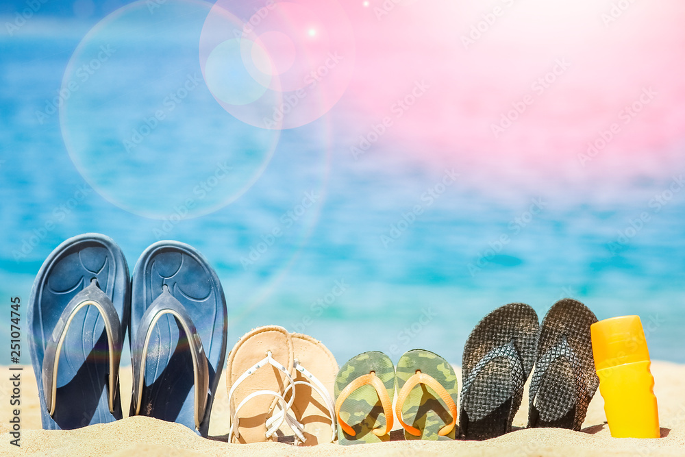 Naklejka premium Stylish beautiful slippers in the sand on the sea background