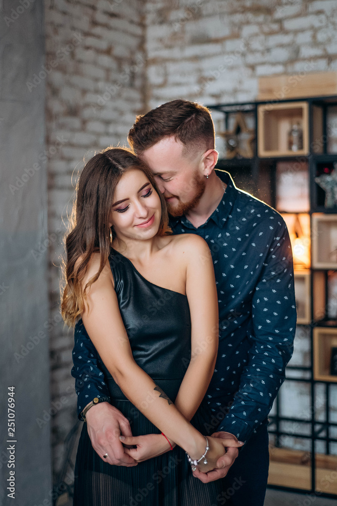 Sensual, romantic couple in love staying and hugging on interior studio background with warm backlight