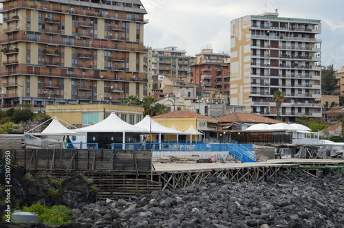 Empty fish market above the black, volcanic beach with new residential buildings in Catania, Sicily, Italy