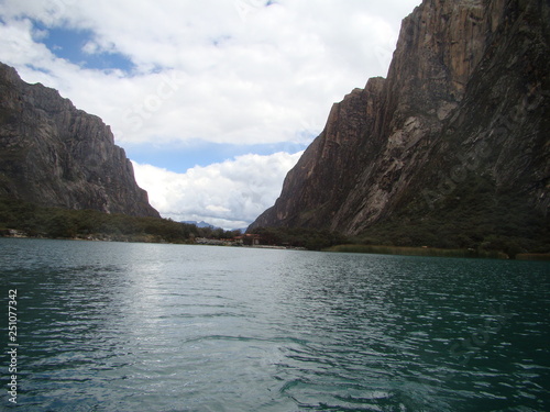 Mountain with snow on top and a turquoise lake below, blue sky with clouds