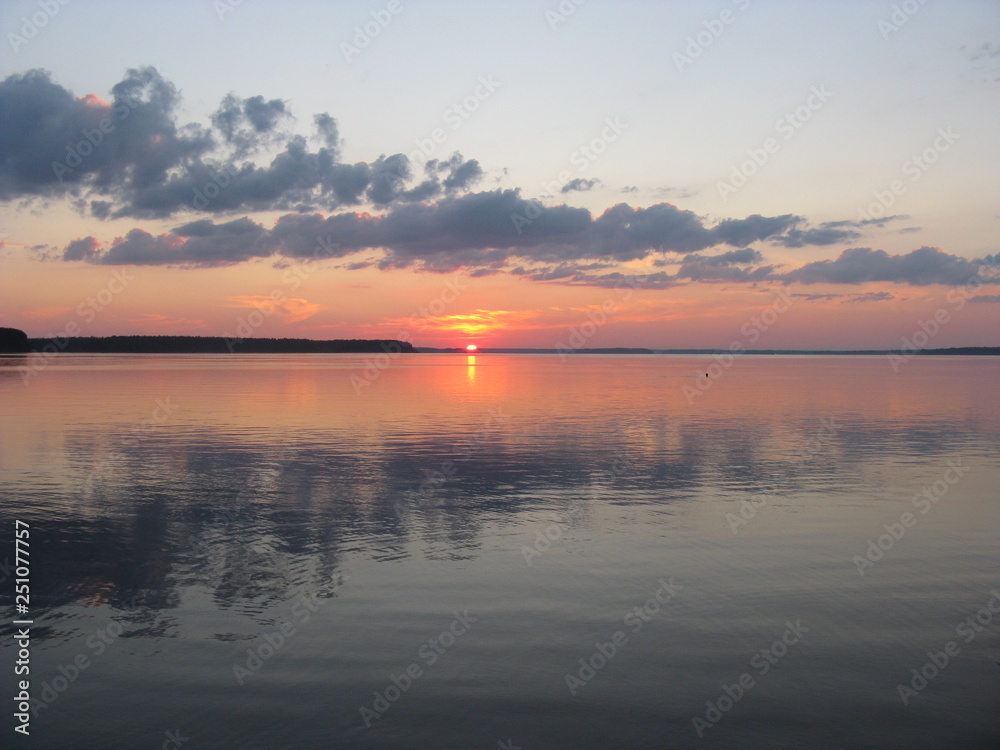 salida del sol sobre lago ruso Seliger con nubes gris y reflejos en agua