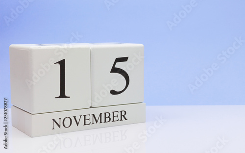 November 15st. Day 15 of month, daily calendar on white table with reflection, with light blue background. Autumn time, empty space for text photo